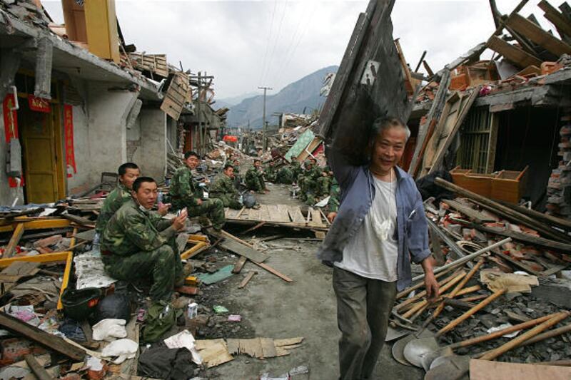 A man carries wood past soldiers taking a break from recovery work in Hongbai in China's Sichuan province on Wednesday.