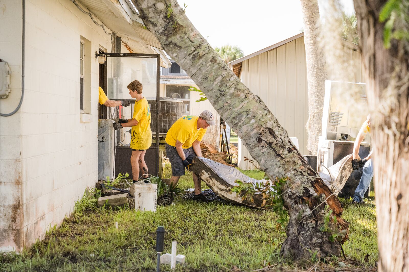 A group of Latter-day Saint volunteers, wearing yellow T-shirts, help to pull water-logged belongings and muck out of a home after Hurricane Idalia in Suwannee, Florida.