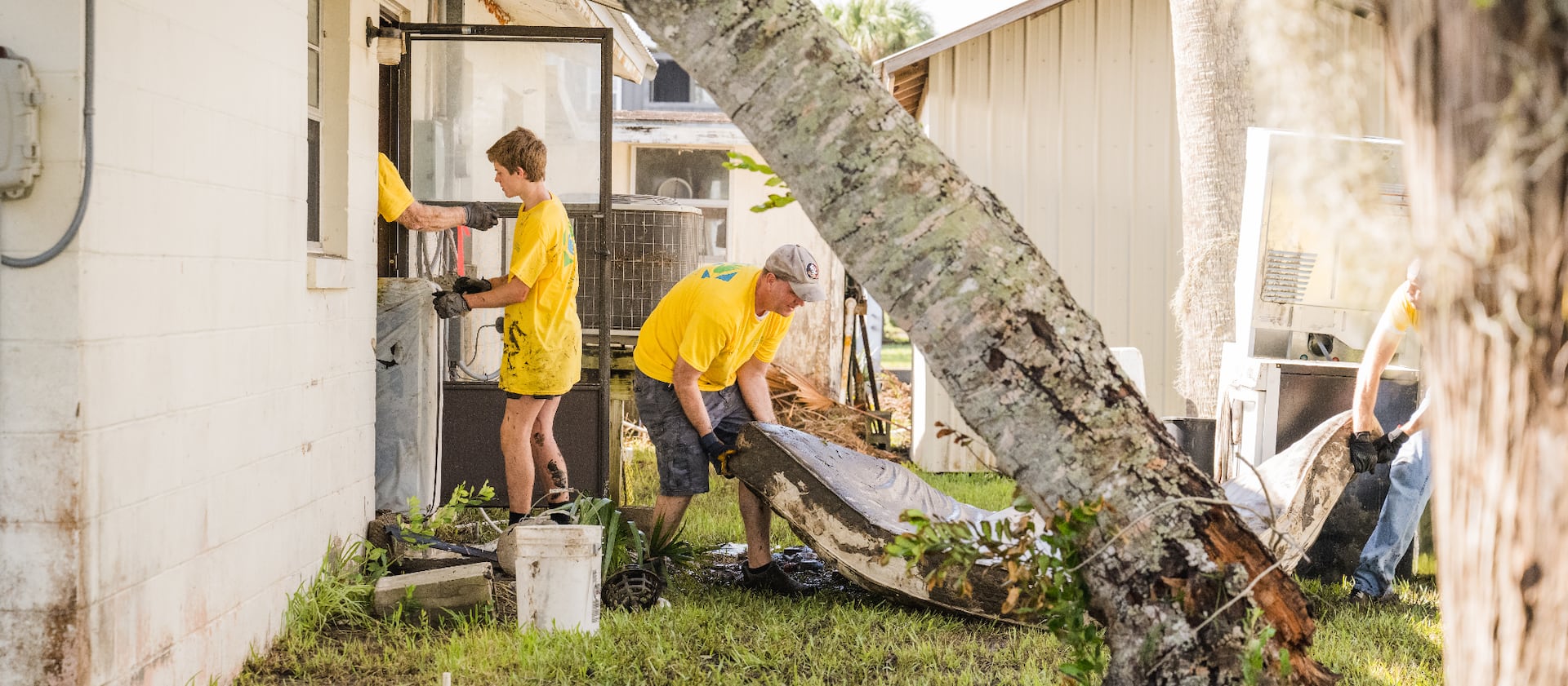 A group of Latter-day Saint volunteers, wearing yellow T-shirts, help to pull water-logged belongings and muck out of a home after Hurricane Idalia in Suwannee, Florida.