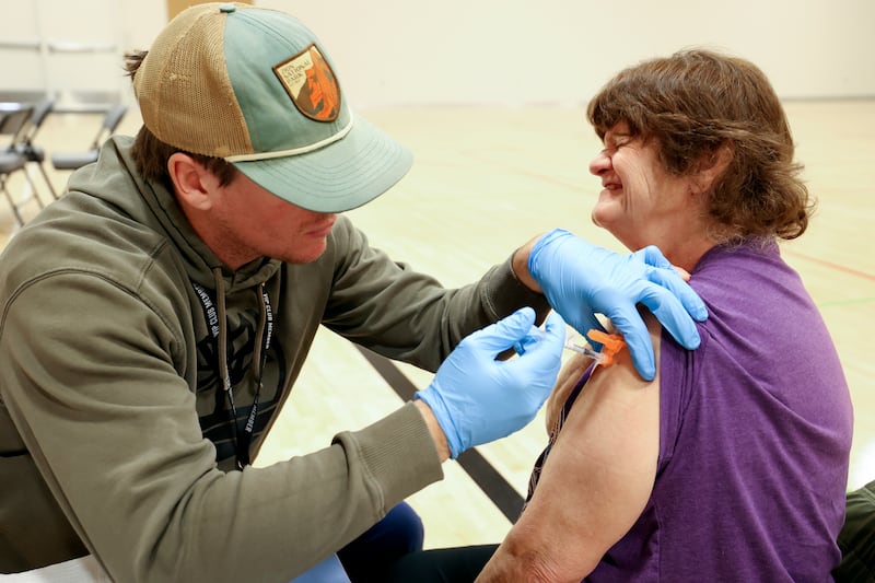 Nurse Wyatt Hanvey gives Lisa Roush a COVID-19 booster shot during a free vaccine clinic in 2022.