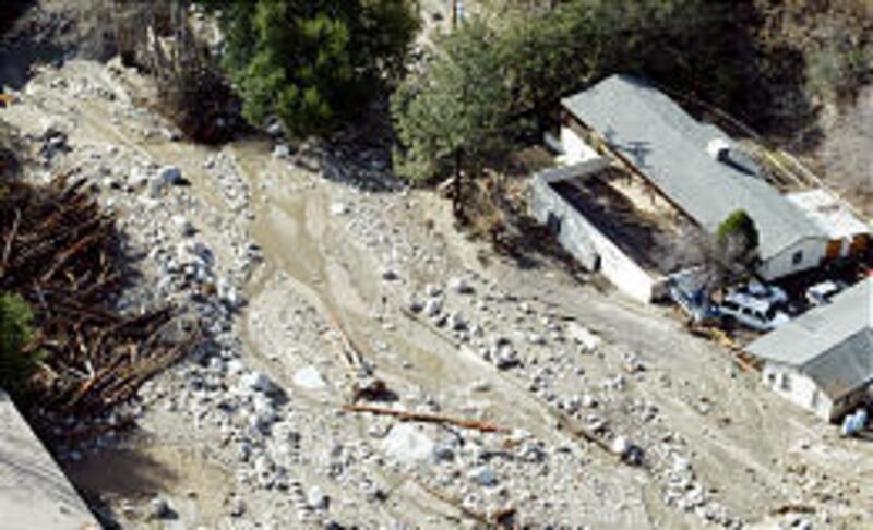 Debris flows past a home in the Waterman Canyon area of the San Bernardino Mountains on Friday after<BR> devastating mudslides swept through the area on Thursday. At least nine people are still missing.