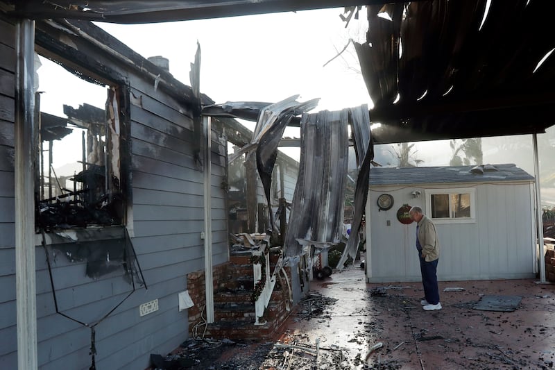 Dick Marsala looks through debris from his destroyed home after a wildfire roared through the Rancho Monserate Country Club Friday, Dec. 8, 2017, in Bonsall, Calif. The wind-swept blazes have forced tens of thousands of evacuations and destroyed dozens of