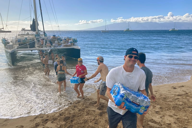A group of volunteers who sailed from Maalaea Bay, Maui, form an assembly line on Kaanapali Beach.