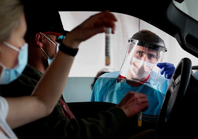 Liz and Sam Rodgers verify their COVID-19 saliva tests to Josh Anderson at a drive-thru test site in South Jordan. Utah.