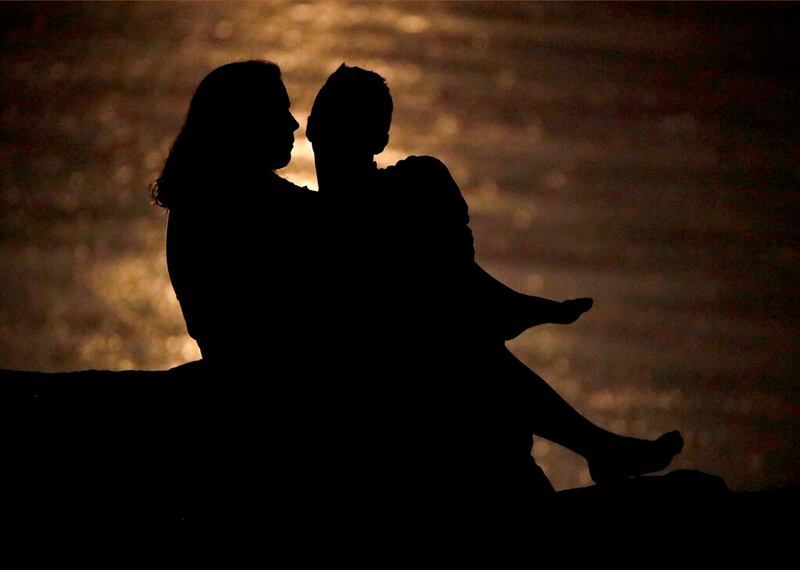 A couple is silhouetted against moonlight reflecting off the Missouri River.