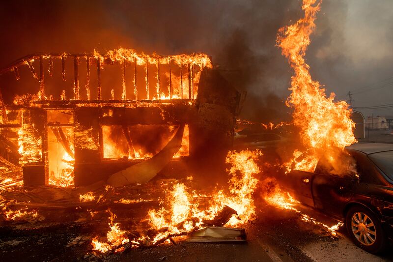Flames consume a car and building as the Camp Fire tears through Paradise, Calif., on Thursday, Nov. 8, 2018.