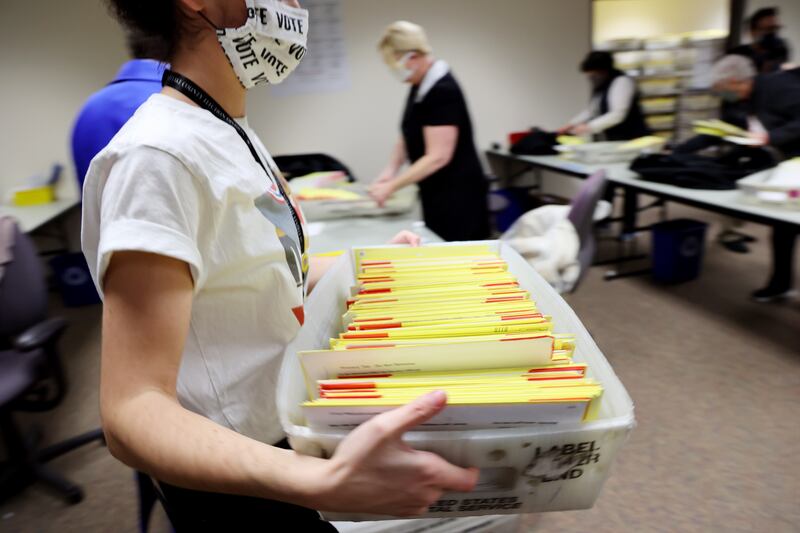 A worker carries a bin of ballots to a rolling cart as election workers process ballots at the Salt Lake County Clerk’s Office in Salt Lake City