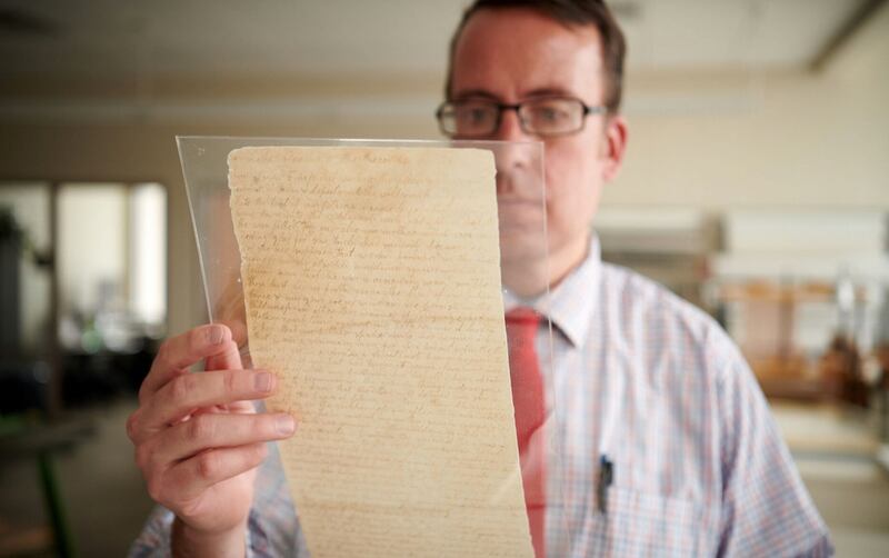 Joseph Smith Papers volume editor Robin Jensen examines a page of the original Book of Mormon manuscript.