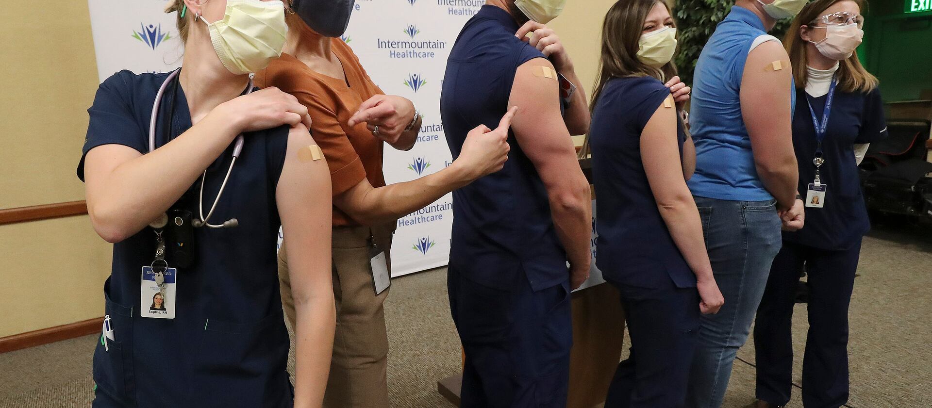 Registered nurses poses for a photo with then-state epidemiologist Dr. Angela Dunn after being vaccinated for COVID-19.