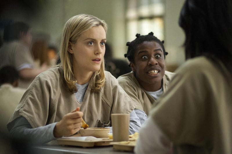 This undated image provided by Netflix shows Taylor Schilling, left, and Uzo Aduba in a scene from the Netflix series, "Orange is the New Black."
