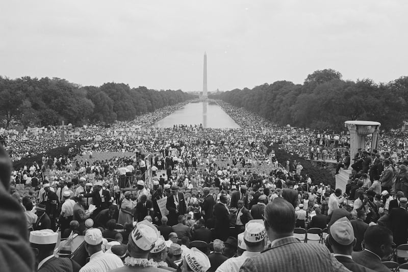 A crowd gathers along the National Mall, with the Washington Monument in the distance.