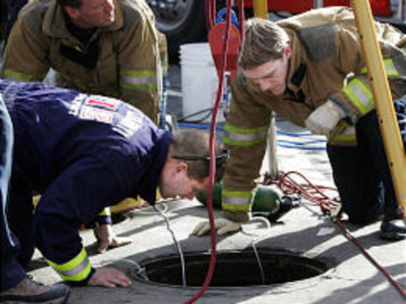 Unified Authority firefighters work to rescue Irene Berrett, who fell 17 feet into a manhole near a grocery store in Draper.