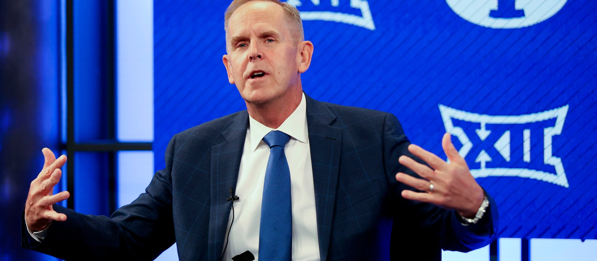 BYU athletic director Tom Holmoe gestures while announcing that BYU has accepted an invitation to the Big 12 Conference.