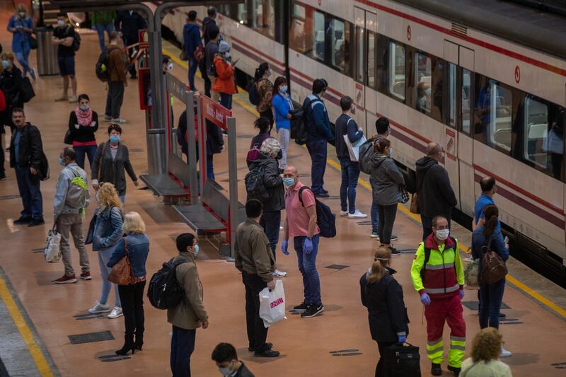 Commuters wearing face masks to protect against coronavirus at the platform of Atocha train station in Madrid, Spain, Spain, Monday, May 4, 2020.