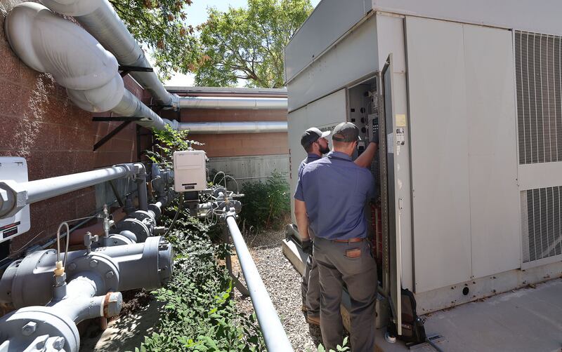 Tooele School District HVAC techs Seth Anderson and Dalton Rydalch look over ae chiller unit that broke down at Tooele High.