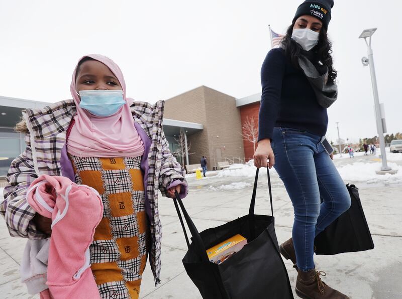 Meadowlark Elementary student Suldana Hussein, left, carries a food bag with the help of Laura Chamorro in Salt Lake City.