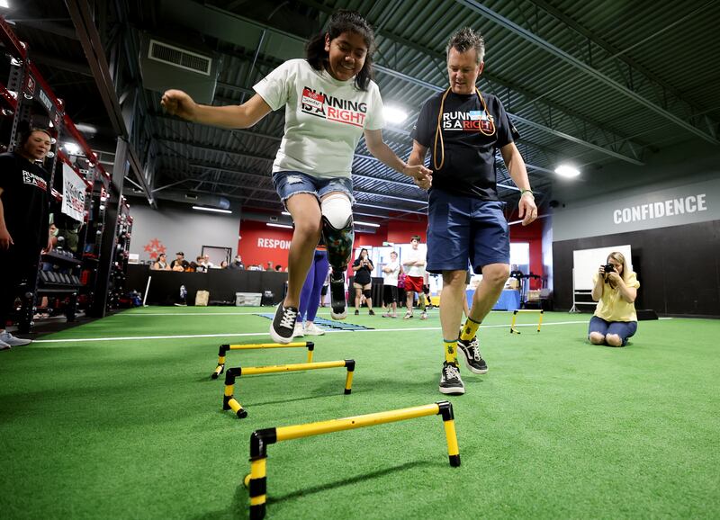 Jennifer Lozano is steadied by Mark Lange from Shriners as she jumps over some obstacles while trying out her new running prostheses.