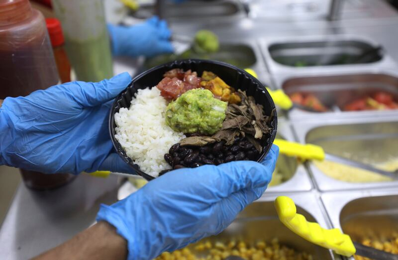 An employees holds a food order at a MUY restaurant, a Colombian fast food chain that is planning to turn its branches into automated restaurants, in Bogota, Colombia, Thursday, Aug. 13, 2020.