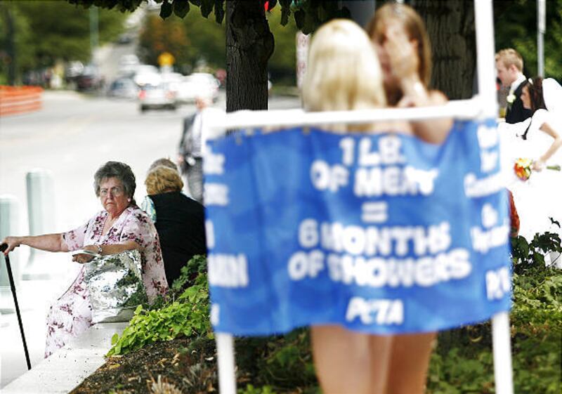 Ruth McEwan, left, of Salt Lake City, looks on with disapproval Friday as two PETA protesters, Ashley Byrne of Washington, D.C., and Cassandra Callaghan of Florida, bathe on the corner of Main and North Temple. "It's disgusting," said McEwan, who had just
