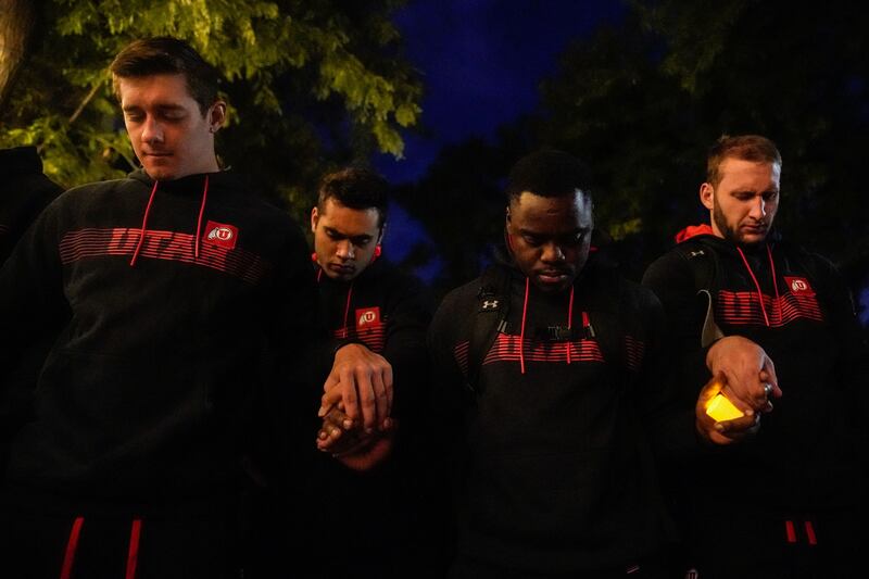 University of Utah football players, wearing black, holding hands pray during a candlelight vigil