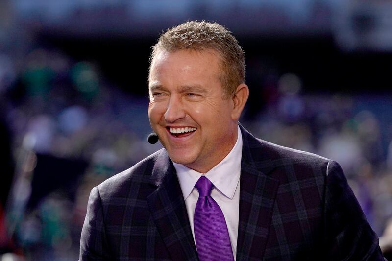 Kirk Herbstreit. wearing a suit, laughs