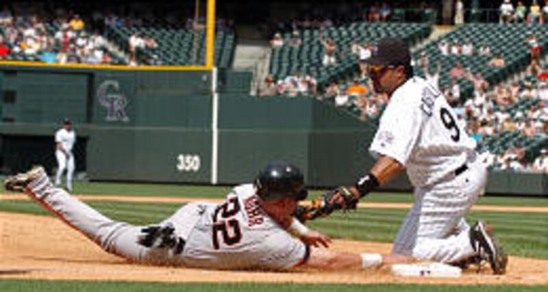 Colorado third baseman Vinny Castilla (9) tags out San Francisco's Dustan Mohr as he tries to advance.