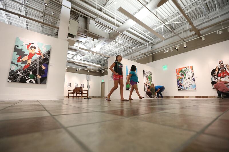 Addie Sperry and friend Sophie Boch walk around the gallery as parents and kids enjoy coloring the different art pieces at the Woodbury Art Museum's "Heroes and Villains: How Mythology Made Comics" exhibition at University Mall in Orem on Tuesday, Aug. 14
