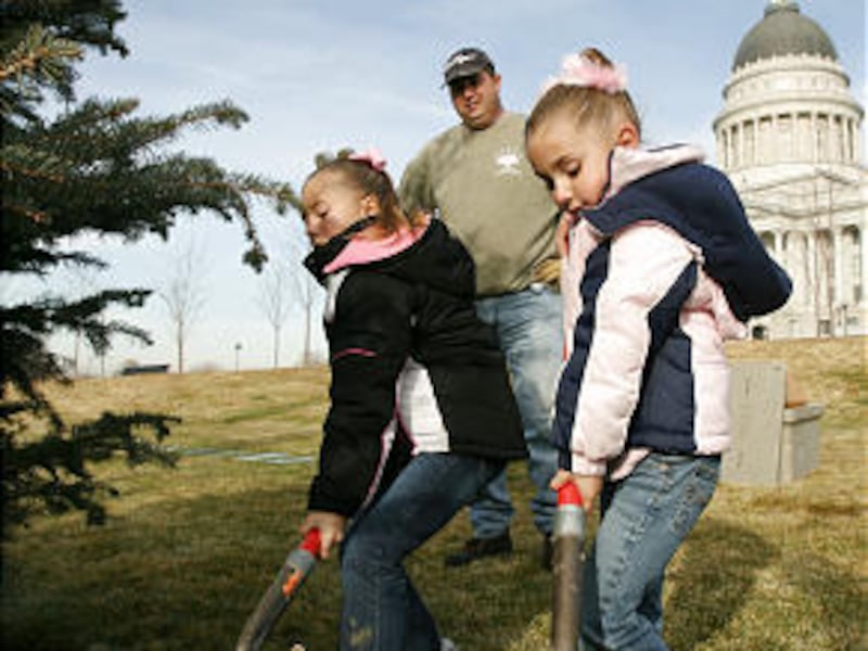 Korissa, left, and her sister Kianna Behunin help plant a Christmas tree as their father, Ben, watches Wednesday.