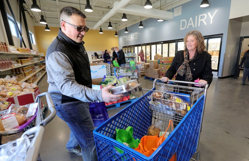 Volunteer Jake Hall helps load up a cart of food for Mindi Sanders at Catholic Community Services Basic Needs in Ogden, Utah.