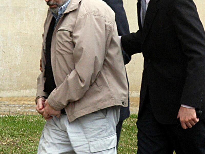 FILE - In this Sept. 30, 2004, file photo, former agent of Chile's past dictatorship Arancibia Clavel, front left, handcuffed and escorted by police officers, arrives to a courthouse in Buenos Aires, Argentina, to attend a trial in connection with the 19