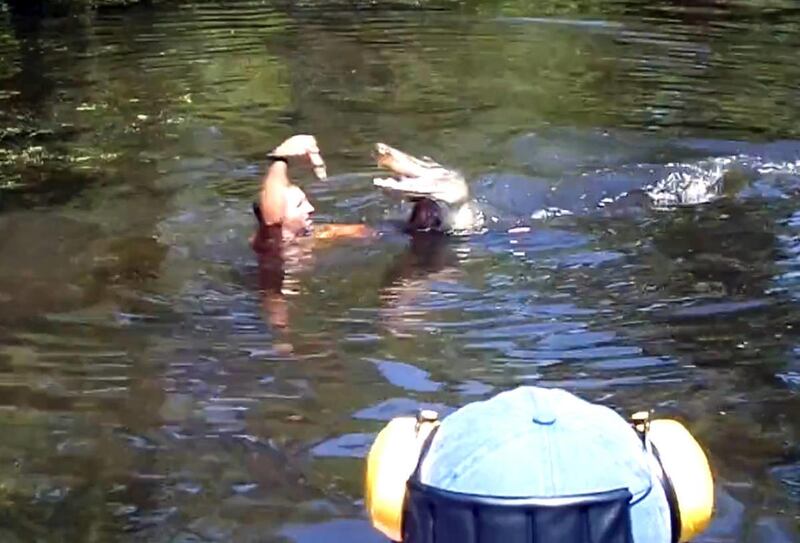 This screen grab from video released by Stacy Hicks shows an unidentified tour guide for Airboat Adventures swimming with and feeding alligators, at one point feeding a marshmallow to a gator with his teeth.