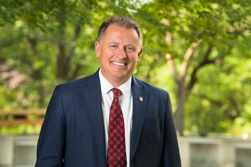 Taylor Randall smiles in front of trees on the University of Utah campus.