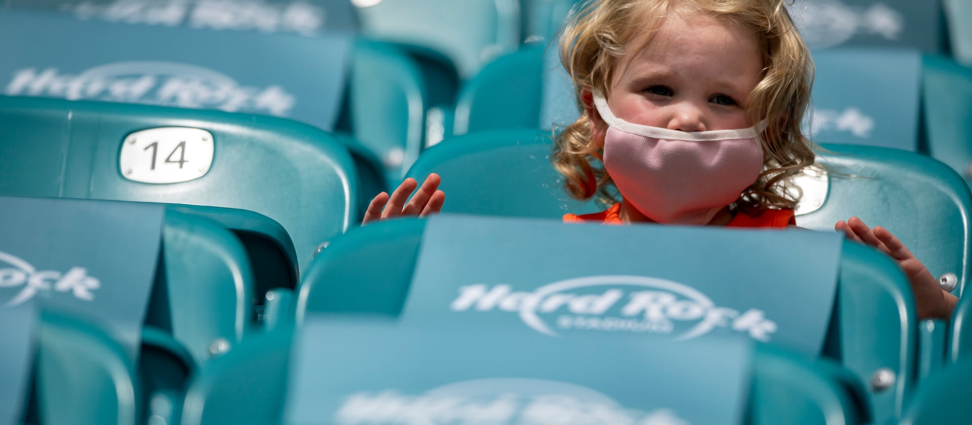 Young female child wears a mask in the socially distance seating at the Hard Rock Stadium before the Seattle Seahawks take on the Miami Dolphins during an NFL football game, Sunday, Oct. 4, 2020, in Miami Gardens, Fla. (