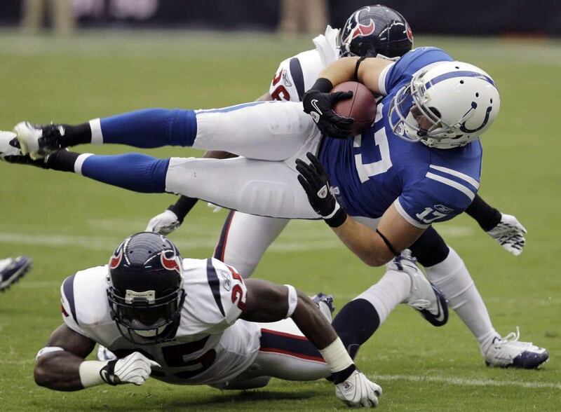 Indianapolis Colts' Austin Collie (17) is upended by Houston Texans defenders Kareem Jackson (25), below, and Eugene Wilson, behind, during the first quarter of an NFL football game Sunday, Sept. 12, 2010, in Houston.