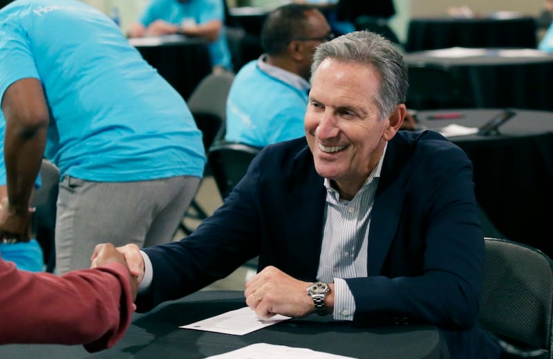 In this May 19, 2017, file photo, Starbucks CEO Howard Schultz, right, shakes hands with a job seeker during the Opportunity Fair and Forum employment event in Dallas. For someone who has given about $150,000 to Democratic campaigns over the years, Schult