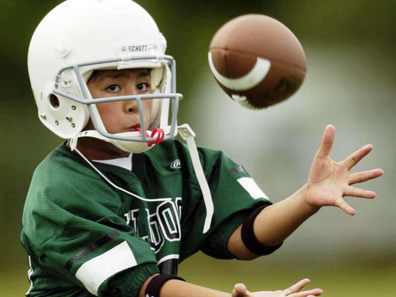 Trae Faumui concentrates on the ball as he takes part in the Dixon Bulldogs little league football practice in Provo. As much of the recent reporting on head injuries in football has focused on legal action taken against the NFL, a couple of authors are t