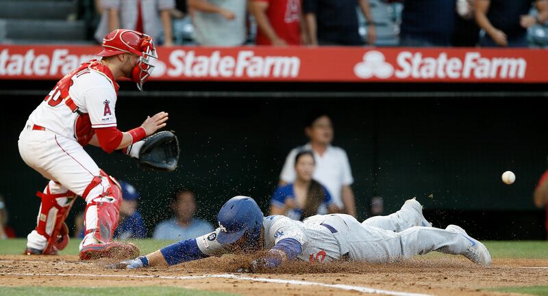 Los Angeles Dodgers' Russell Martin, right, beats the throw from left field to Los Angeles Angels catcher Jonathan Lucroy, left, to score with Corey Seager on a double by Chris Taylor during the second inning of a baseball game in Anaheim, Calif., Monday,