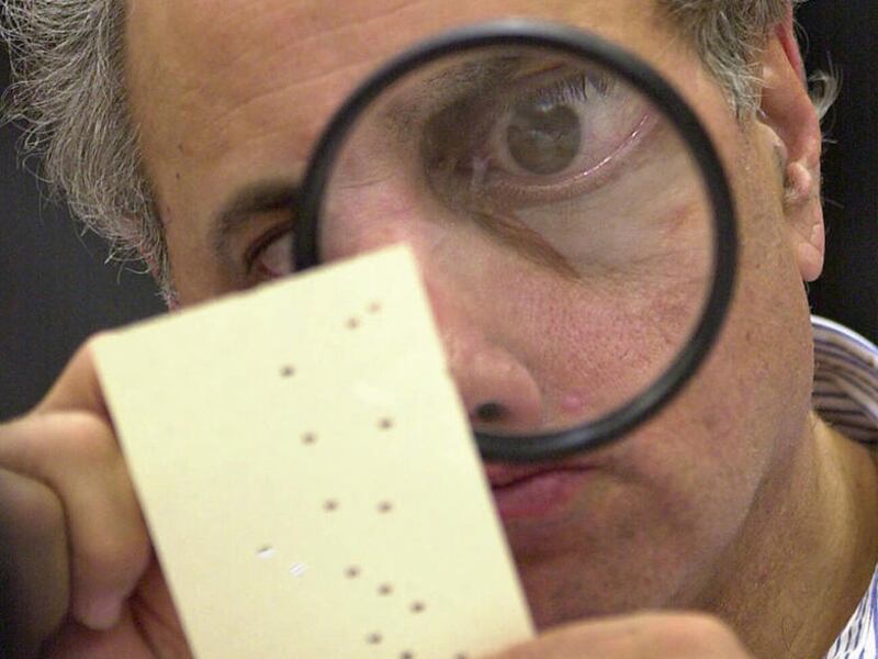 FILE - In this Nov. 24, 2000 file photo, Broward County canvassing board member Judge Robert Rosenberg uses a magnifying glass to examine a disputed ballot at the Broward County Courthouse in Fort Lauderdale, Fla. Donald Trump, who"™s railed for months ab