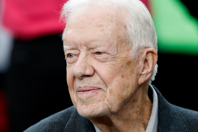 Former President Jimmy Carter sits on the Atlanta Falcons bench before an NFL football game between the Falcons and the San Diego Chargers in 2016.
