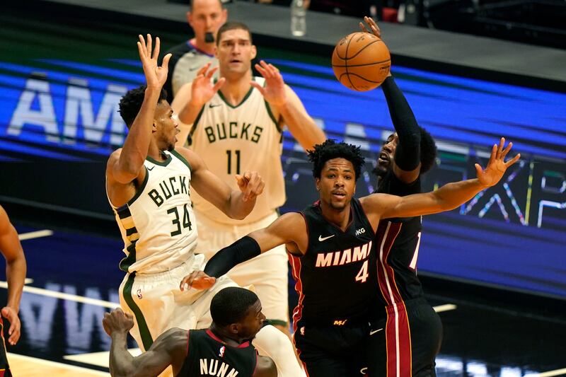 Miami Heat center Bam Adebayo, right, blocks a pass by Milwaukee Bucks forward Giannis Antetokounmpo (34) during the first half of an NBA basketball game, Tuesday, Dec. 29, 2020, in Miami. At right is Miami Heat forward KZ Okpala (4).