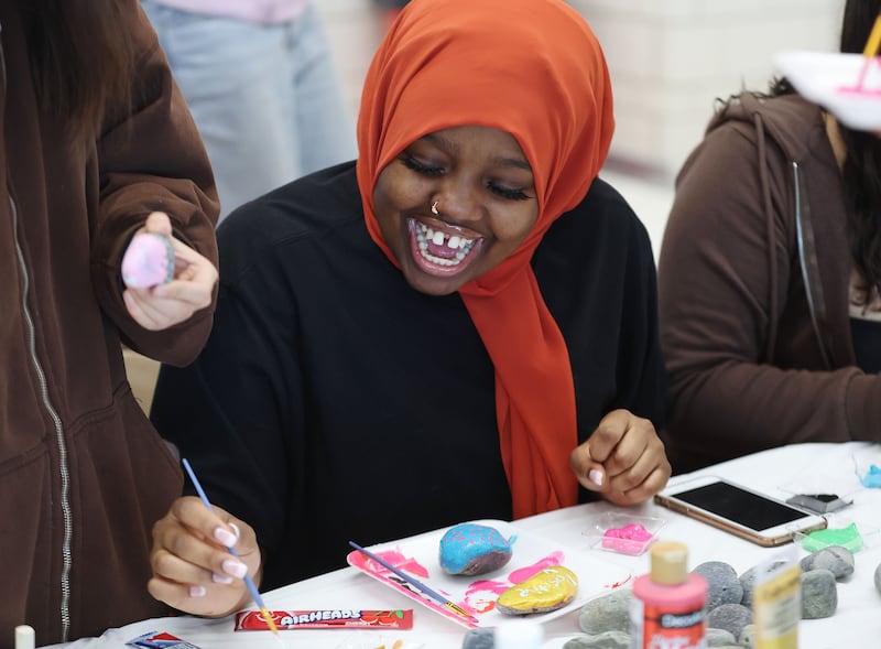 East High School student Fadumo Aden has fun painting a rock that has a kind message on it in Salt Lake City.