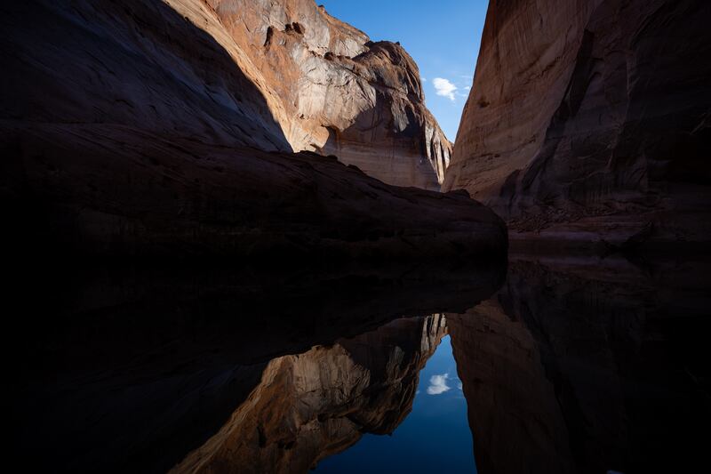 Light and shadows on the canyon walls of Davis Gulch are reflected in the reservoir’s waters.