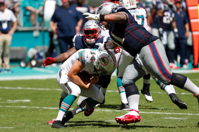 Miami Dolphins quarterback Ryan Fitzpatrick ducks as New England Patriots outside linebacker Elandon Roberts and defensive tackle Danny Shelton close in for a sack during a Sunday, Sept. 15, 2019, game in Florida.