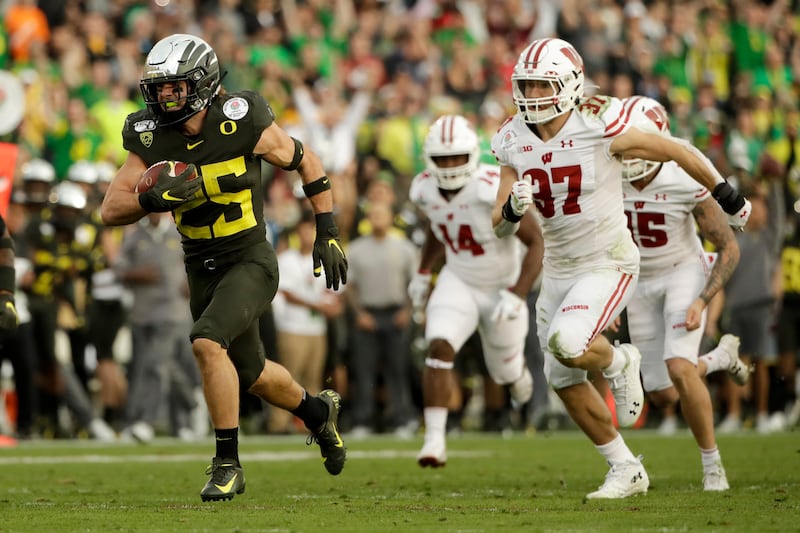 Oregon safety Brady Breeze, left, runs for a touchdown past Wisconsin running back Garrett Groshek