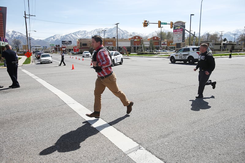 Two officers run to a car and speed off after a man driving a white pickup truck crashed into Princess Alterations, 3339 S. State, in South Salt Lake on Monday, April 8, 2019. The driver of the pickup, who was suspected of committing two robberies and who