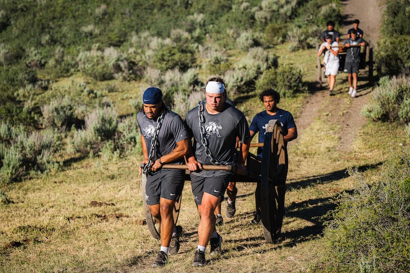 Utah State football players push a hand cart up a ridge during a trek of Cache Valley at the direction of second-year head football coach Bronco Mendenhall.