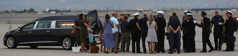 Members of the Draper City Fire Department and Unified Fire Authority Honor Guard stand with family members after the casket of Draper Battalion Chief Matt Burchett is placed in a hearse after being transported from California to Utah in a C130-J by the C