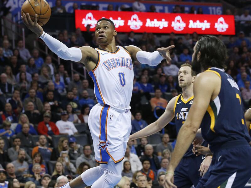 Oklahoma City Thunder guard Russell Westbrook (0) shoots in front of Utah Jazz forward Joe Ingles, center, and guard Ricky Rubio, right, during the first quarter of an NBA basketball game in Oklahoma City, Wednesday, Dec. 20, 2017. (AP Photo/Sue Ogrocki)