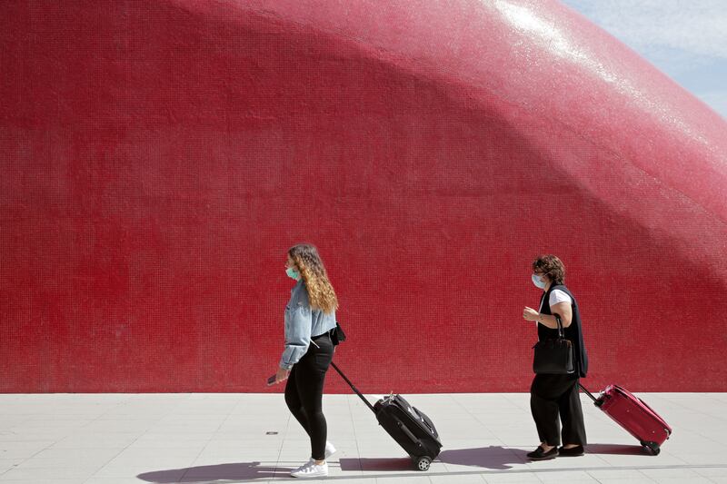 Two women wearing face masks pull their suitcases outside Lisbon’s airport, Friday, Sept. 11, 2020.