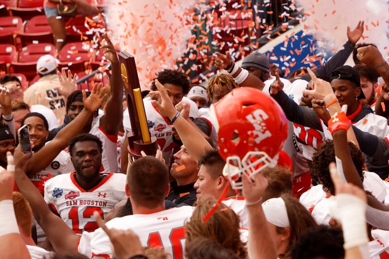 Sam Houston State head coach K.C. Keeler hoists the championship trophy after defeating South Dakota State 23-21 for the NCAA college FCS Football Championship.